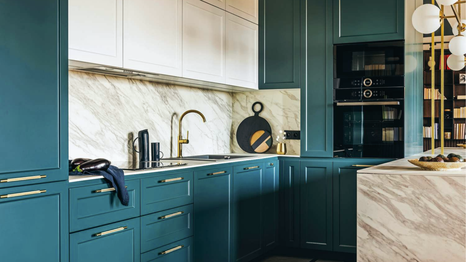Deep teal cabinets with white uppers, marble backsplash, gold fixtures, bold jewel tone color scheme