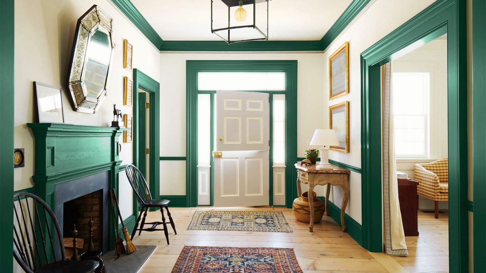Traditional entryway featuring bold emerald green trim paint on door casings, crown molding, and fireplace mantel against cream walls