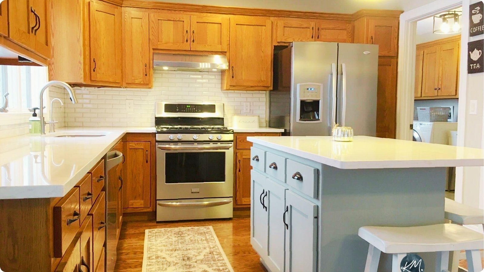 Classic farmhouse kitchen featuring natural honey oak cabinets paired with a light blue painted island and white quartz tops.