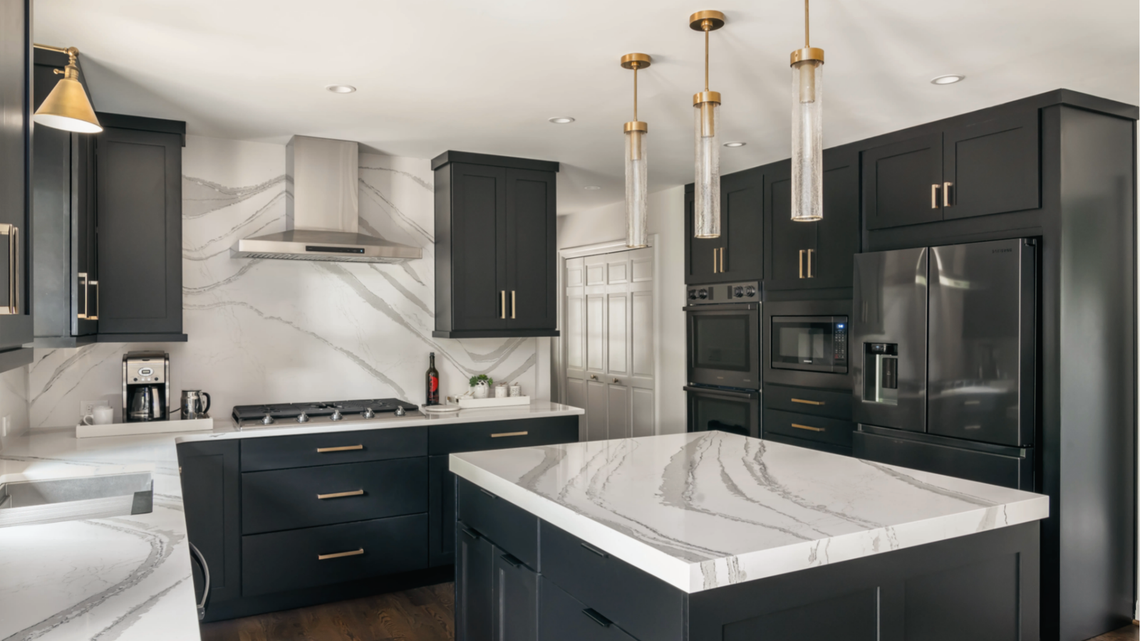 Black cabinets, white veined marble counters, gold accents, brass pendants, luxury dark kitchen palette