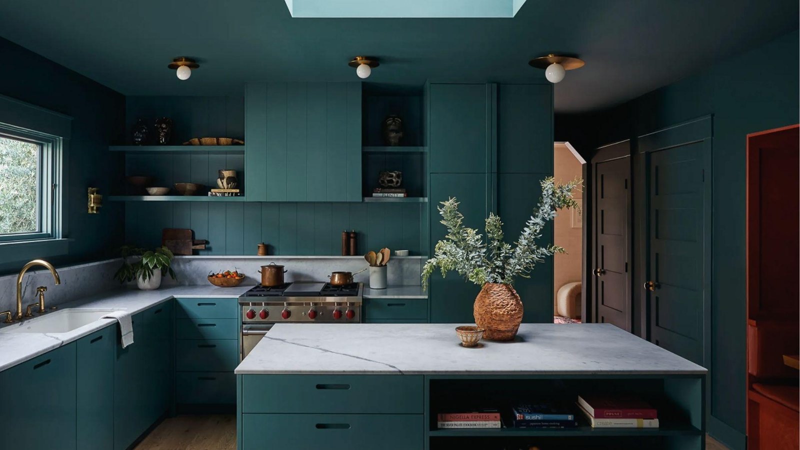 Teal cabinets and walls, white marble counters, brass fixtures, bold color-drenched kitchen palette