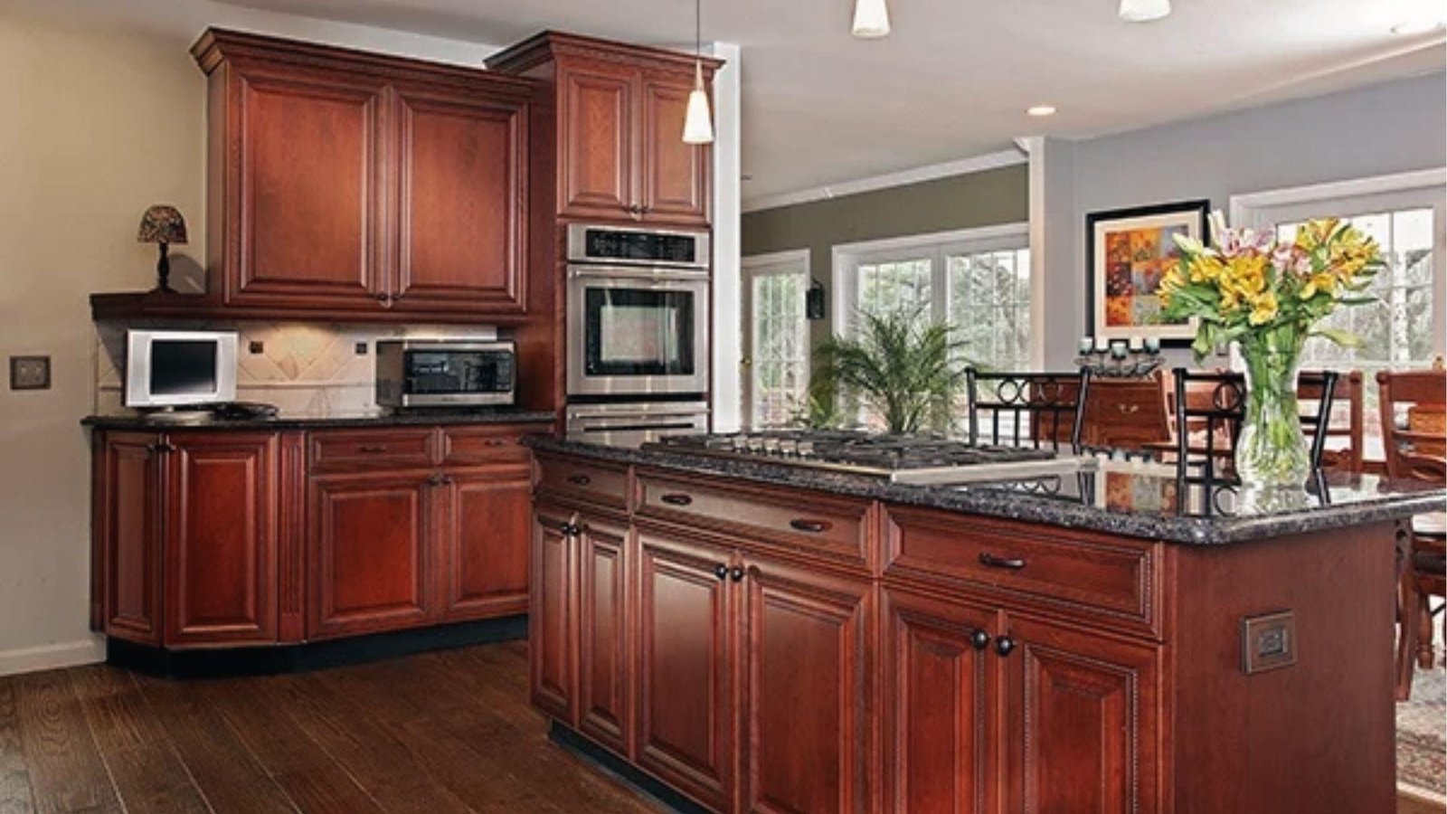 Traditional kitchen with rich cherry wood cabinets, brown granite, stainless steel fridge.