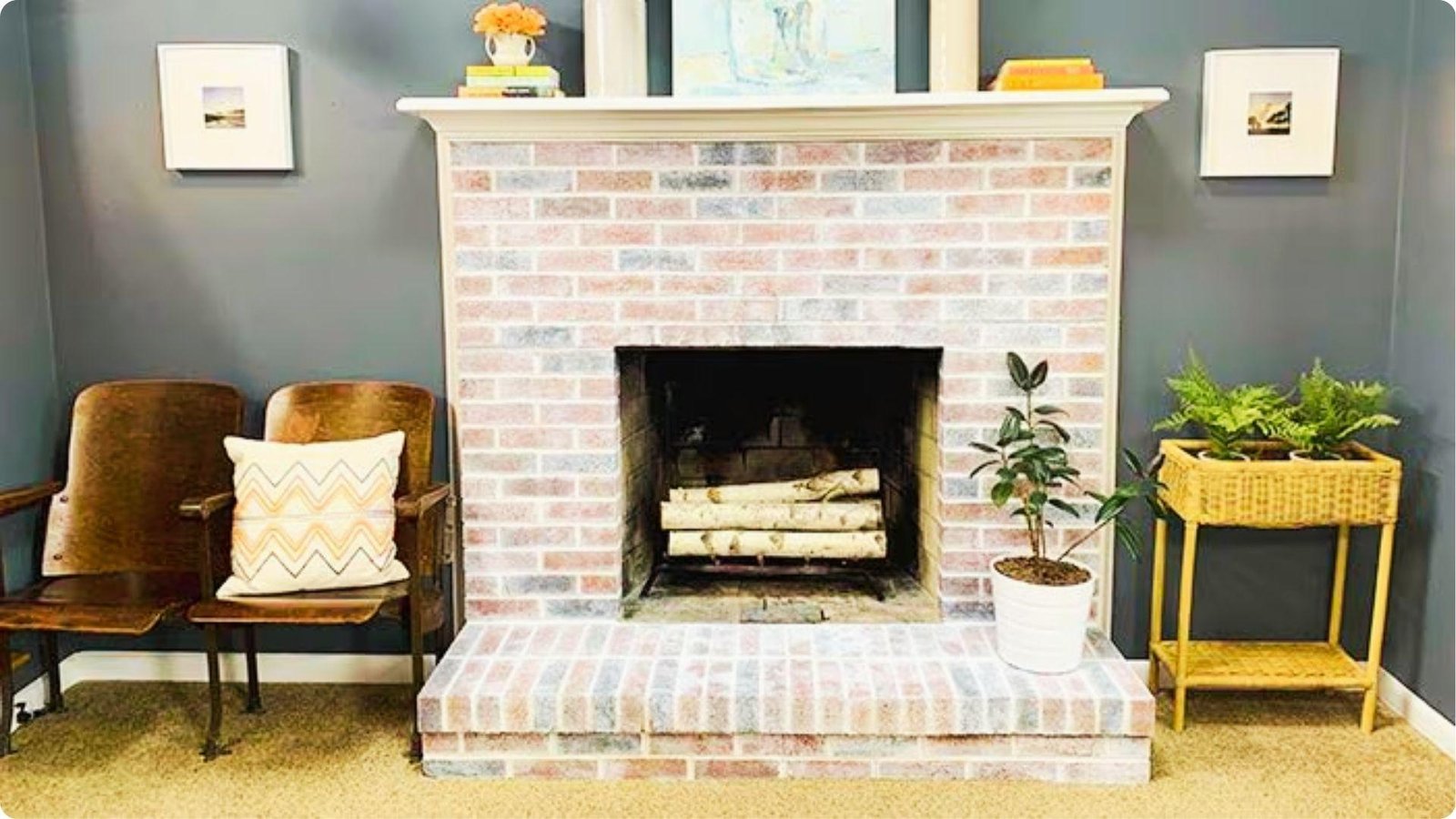 A finished brick fireplace with a light whitewashed effect sits between two chairs and plants.