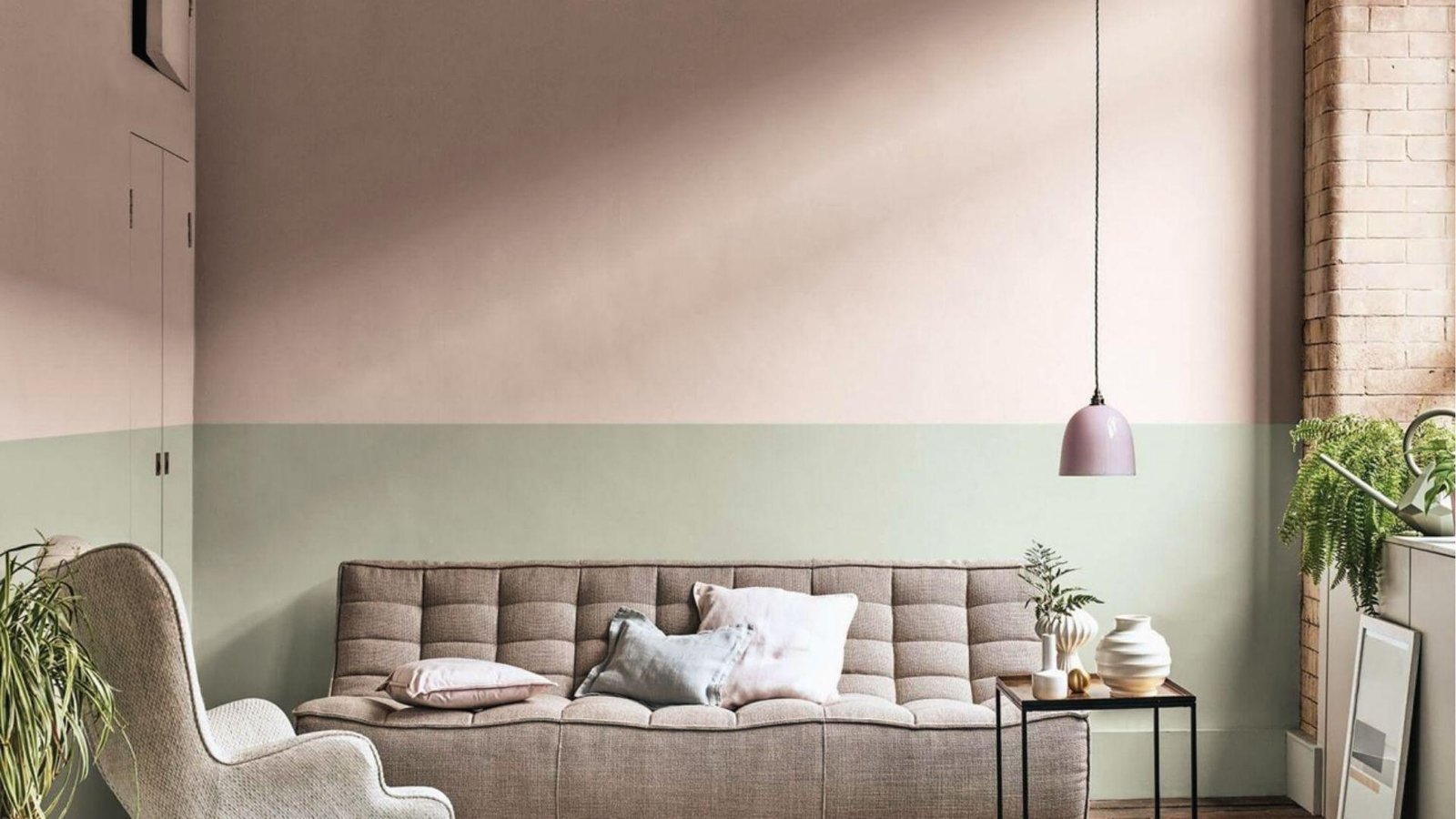 Cozy lounge with blush pink upper and sage green lower two tone wall behind tufted sofa set.