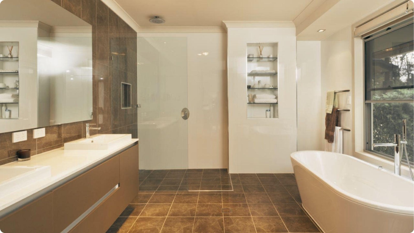 Spacious bathroom with white painted walls, dark brown tile accents, dual vanities, and a freestanding bathtub by a large window.