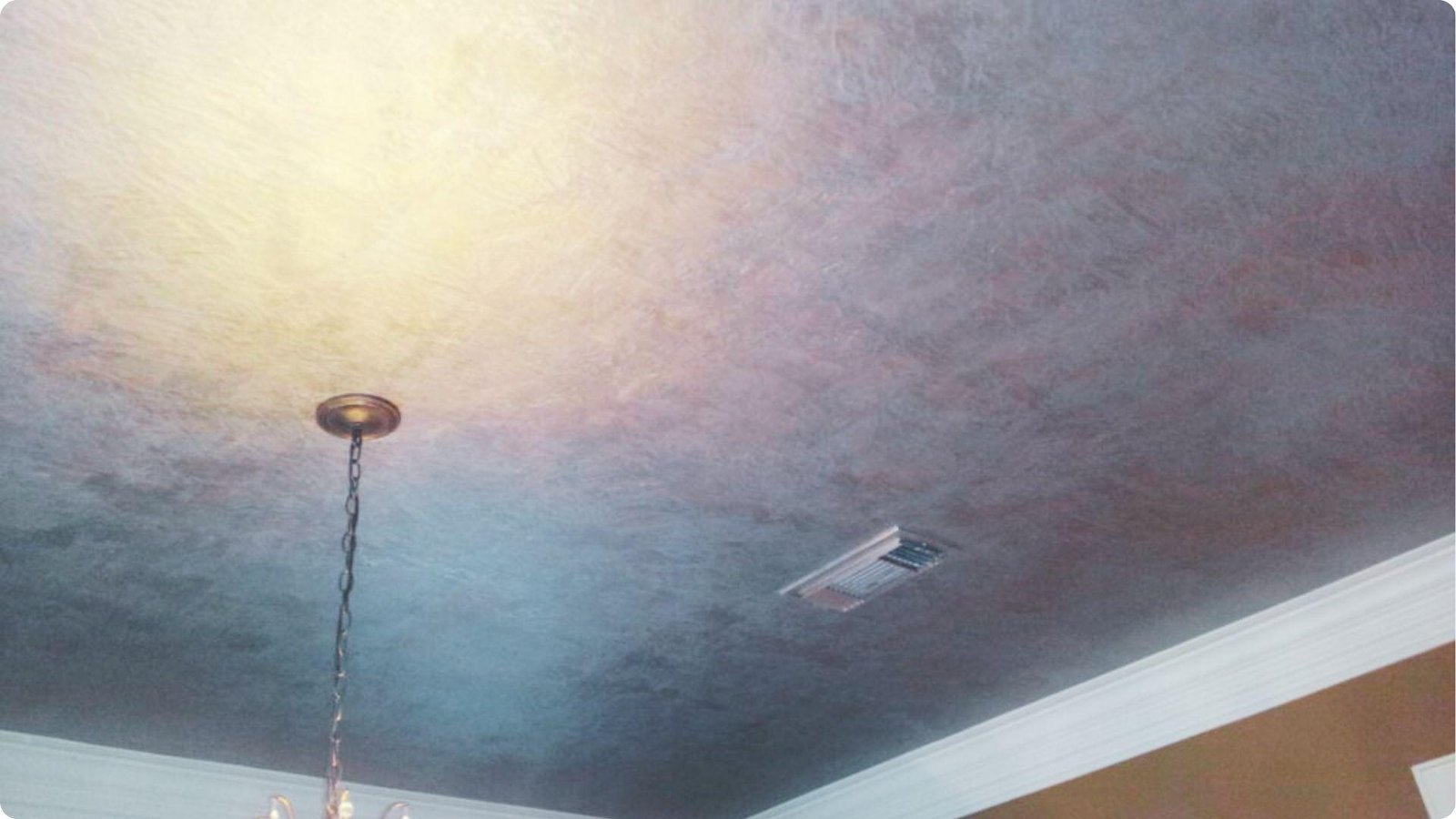 Metallic color-wash faux finish on a ceiling with soft gold to slate blue tones.