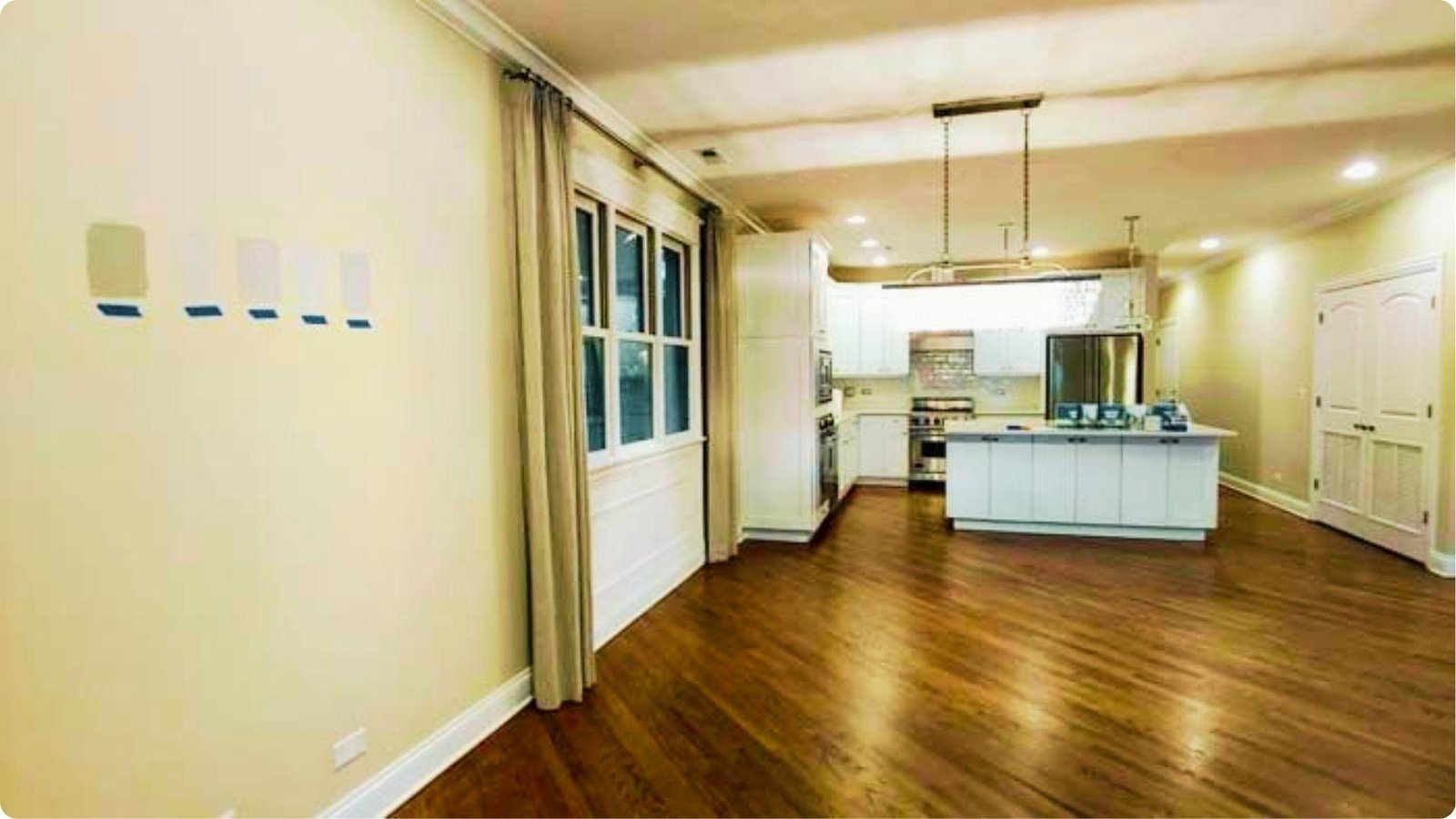 Open kitchen and living area with multiple paint swatch samples taped to the wall.