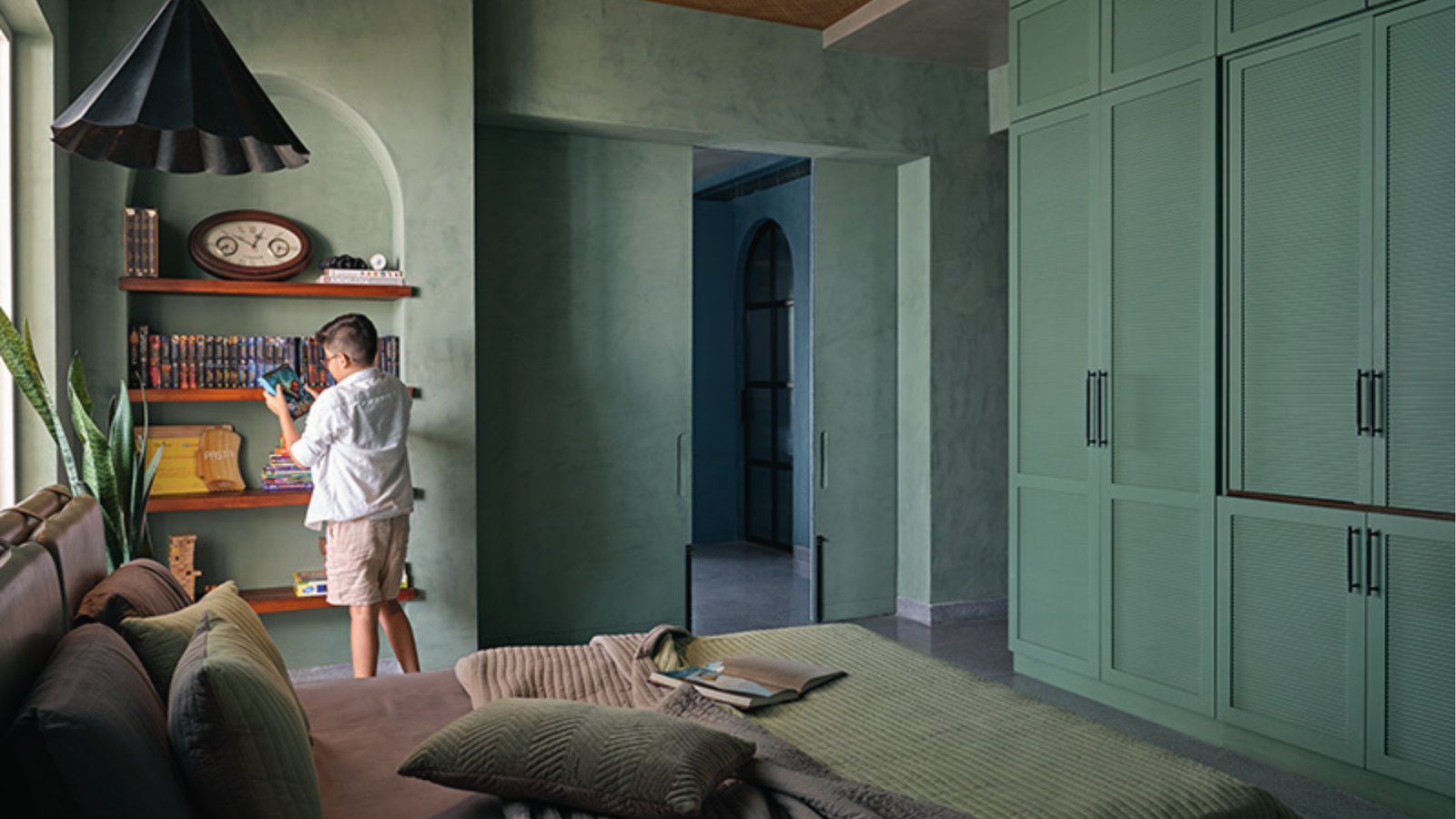 Kids bedroom with textured teal green walls, built-in wardrobes and bookshelf for bold style.-
