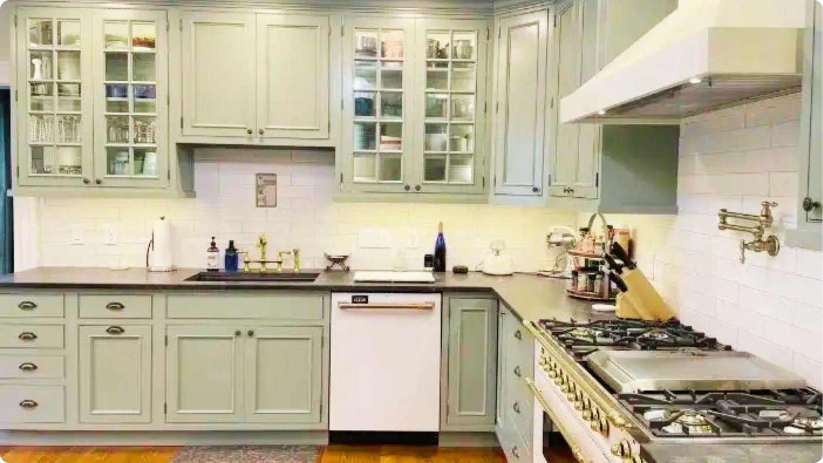 Traditional farmhouse kitchen with pale sage green painted cabinets, glass door uppers, and white subway tile backsplash.