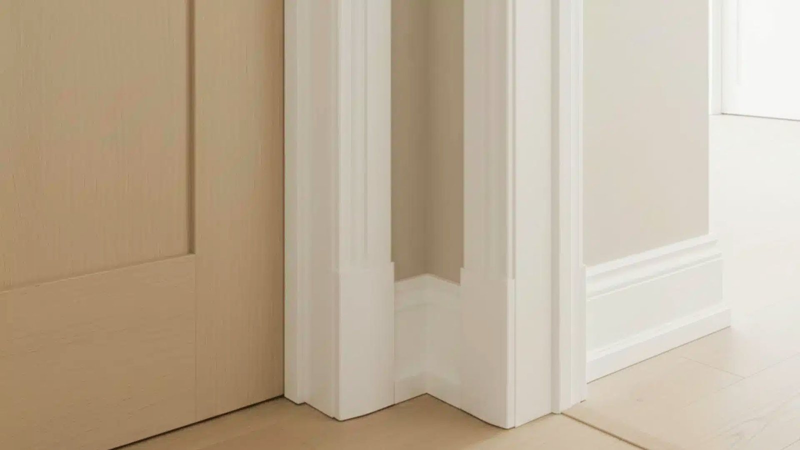 Close-up of crisp white trim paint on door casing and baseboards against beige walls highlighting clean trim work