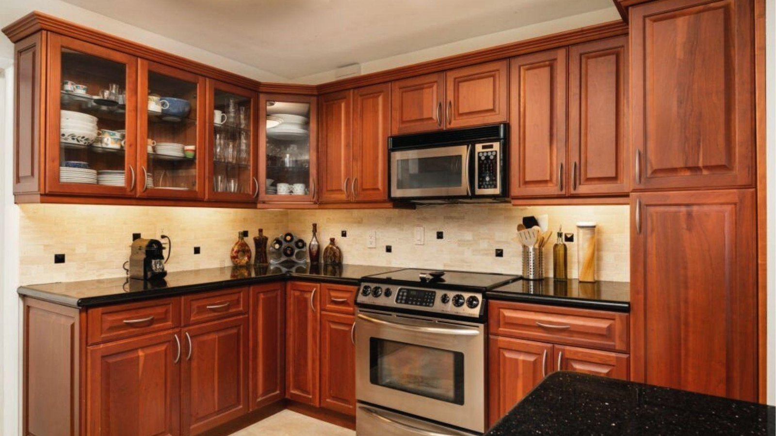 Mid-tone cherry wood kitchen cabinets, black granite counters, stainless steel appliances.