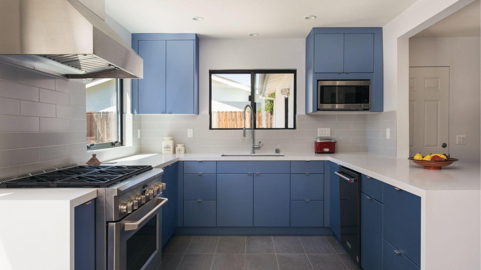 Matte blue cabinets, white quartz counters, gray tile backsplash, bright modern cool color scheme