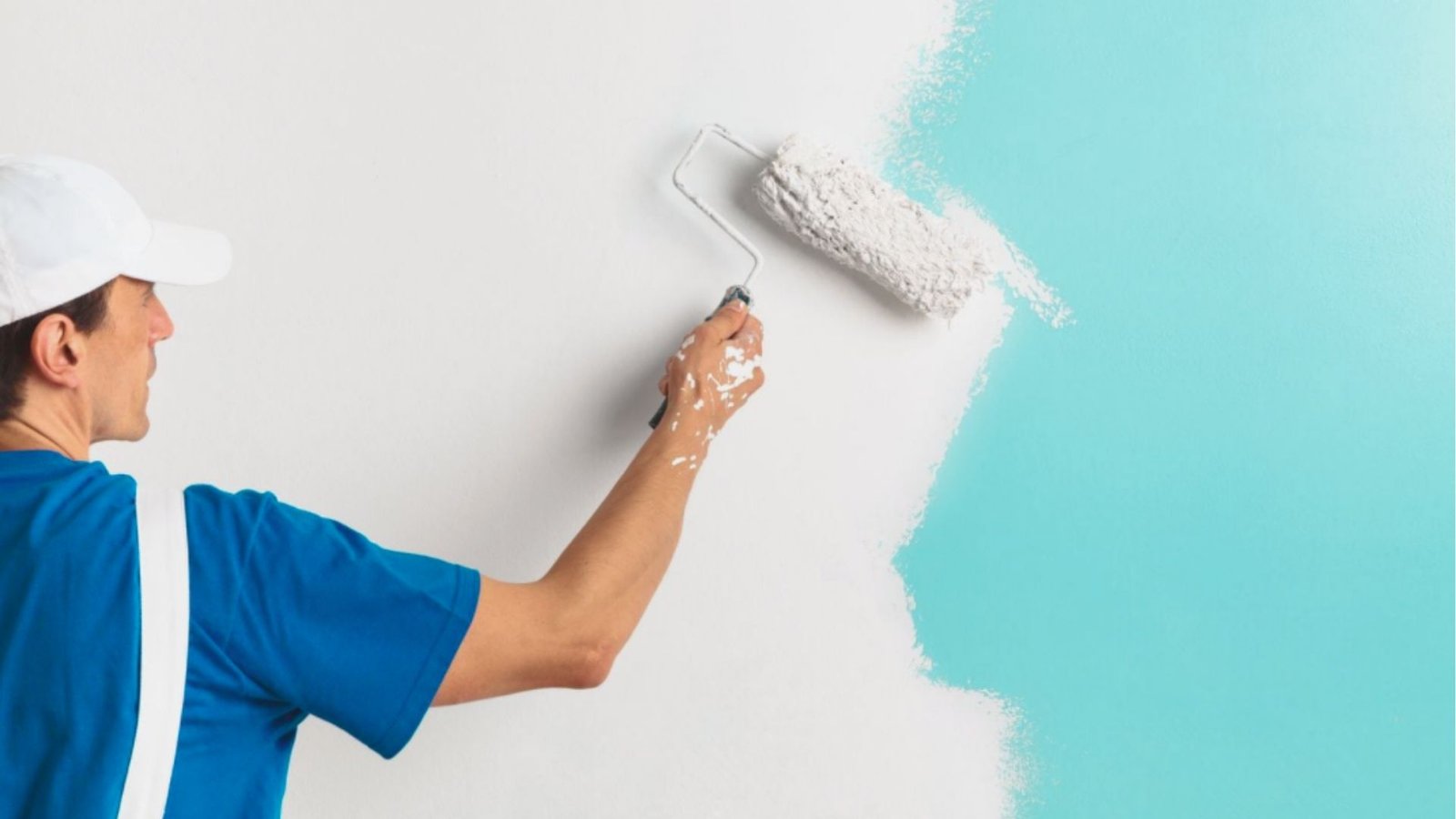 A man using a paint roller to apply color to a wall in a home improvement project.